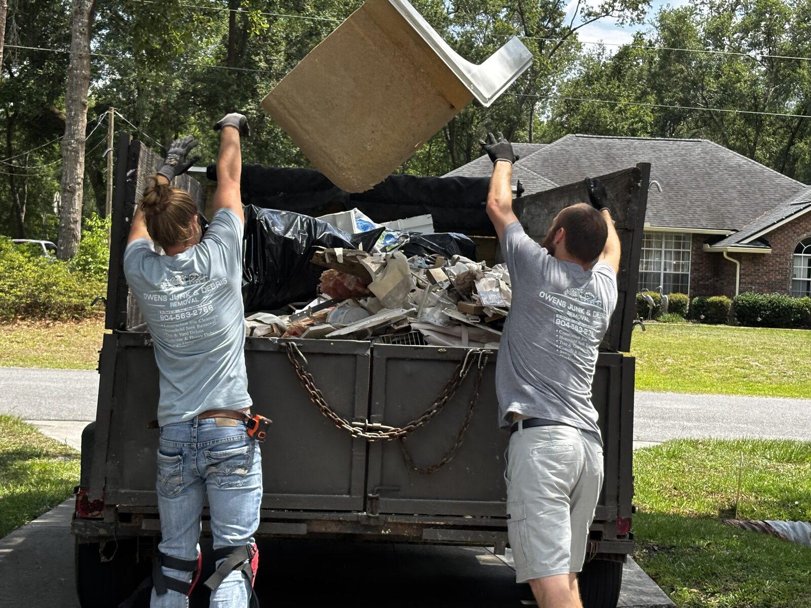 Owen's Junk & Debris Removal crew loading construction debris onto trailer in Jacksonville, FL